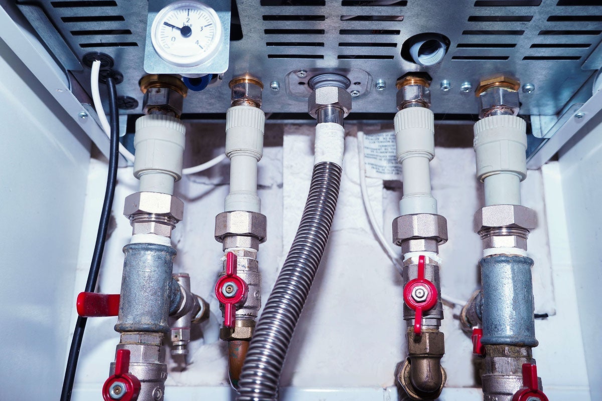 A close-up shows pipes and valves connected to a boiler, with a pressure gauge visible.